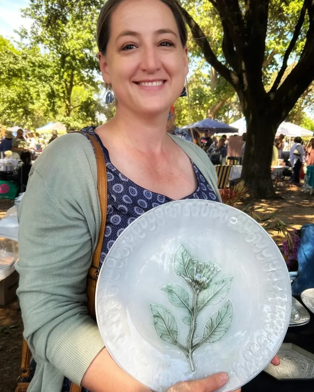 Nada Spencer at an outdoor market, holding a white plate with a printed botanical design