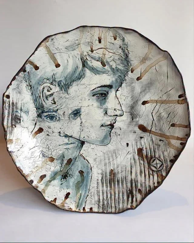 Round plate with two overlapping monoprinted portrait faces in blue and white, notched rim