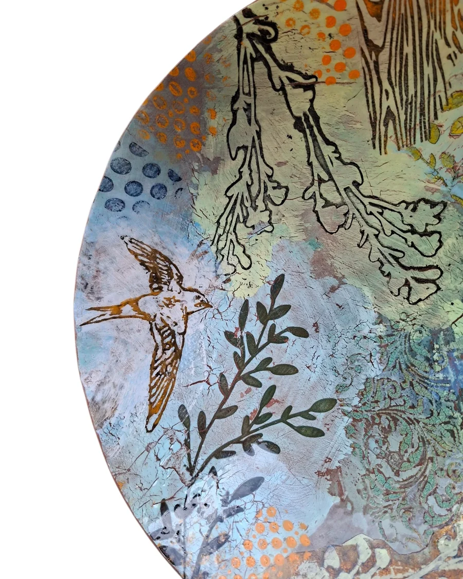 Detail of a large round platter with a bird and botanical drawing over layered slip and underglaze